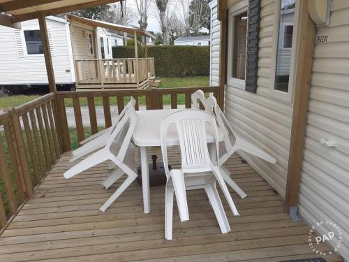 - une table et des chaises blanches sur une terrasse couverte dans l'établissement Mobile Home Carnac, à Carnac