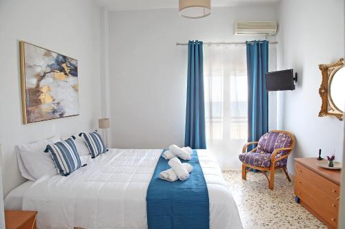 een slaapkamer met een bed met blauwe gordijnen en een stoel bij Nami Sea View Near Airport Apartment in Artemida