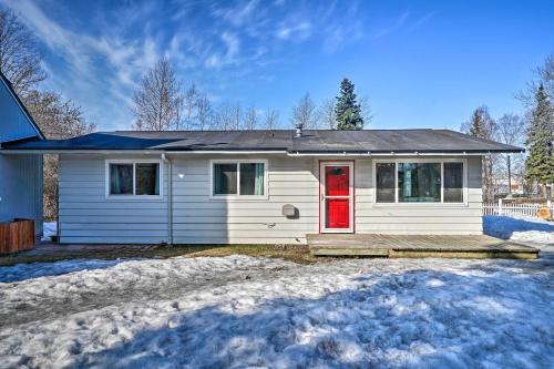 ein weißes Haus mit einer roten Tür im Schnee in der Unterkunft Relaxing Anchorage Home about 1 Mi to Downtown! in Anchorage