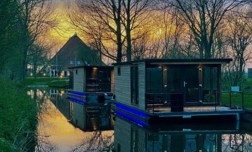 twee tiny houses op het water bij zonsondergang bij Waterlodges WeidumerHout in Weidum