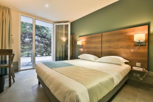 ein Schlafzimmer mit einem großen Bett und einem großen Fenster in der Unterkunft Vent d'Eden Park Hôtel in Saint-Hilaire-de-Riez