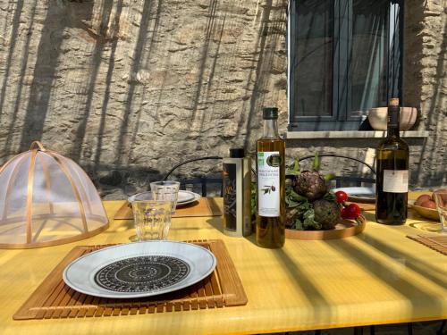 una mesa con un plato y dos botellas de vino en Superbe maison dans village au coeur de la Corse A casa Suttana, en Verdese