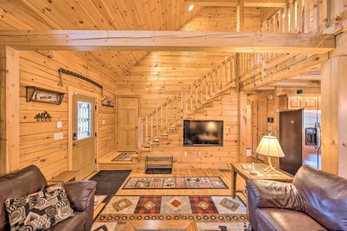 a living room with a tv and stairs in a log cabin at 9 Mi to Bretton Woods Carroll Log Cabin with Deck in Carroll