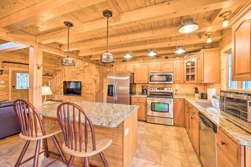 a kitchen with wooden cabinets and a counter with two chairs at 9 Mi to Bretton Woods Carroll Log Cabin with Deck in Carroll