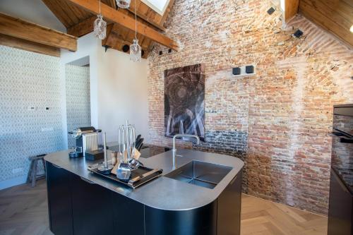 a kitchen with a sink and a brick wall at Luxe appartementen Havenzicht in Sint Annaland
