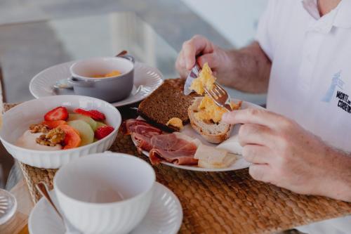 a man is eating a sandwich and a bowl of fruit at Monte dos Cordeiros in Vila Viçosa