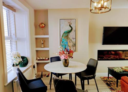a living room with a table and a peacock painting at Tralee Townhouse Holiday Home by Trident Holiday Homes in Tralee