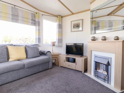 a living room with a couch and a tv and a fireplace at The Maples in Millom