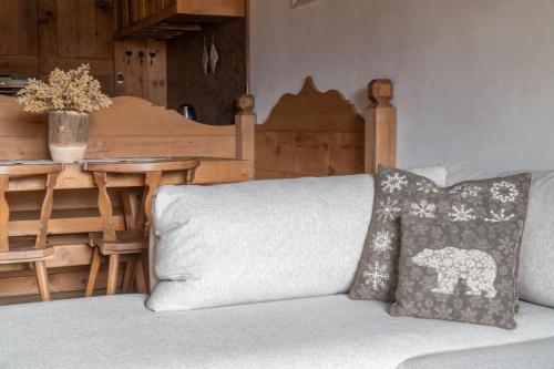 a couch with a pillow on it with a table at Cortina Lodge Stunning View R&R in Cortina dʼAmpezzo