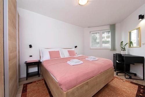 a bedroom with a bed with pink sheets and a piano at Apartments Villa Mili in Brela
