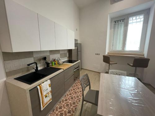 a kitchen with white cabinets and a sink and a table at La Casina sul mare in Giovinazzo