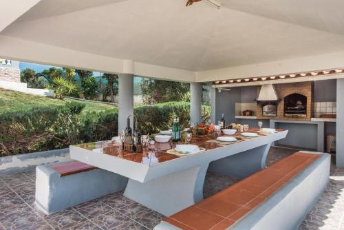 an outdoor kitchen with a table and benches at Villa Cadre - 5BR w Private Pool & Snooker Table in Armação de Pêra