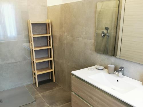 a bathroom with a sink and a mirror and a shelf at Villa Felicia in Noto