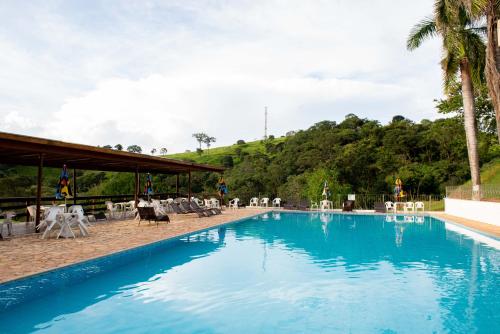 uma grande piscina com cadeiras e árvores ao fundo em Hotel Fazenda Vale da Cachoeira em Serra Negra