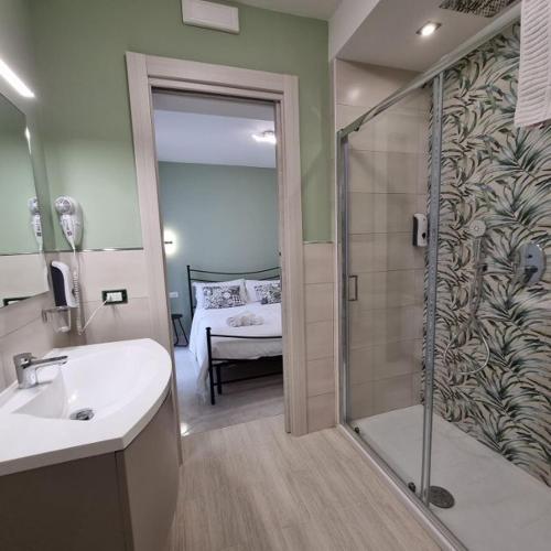 a bathroom with a sink and a shower with a bed at Appartamento Mattia in Marsala