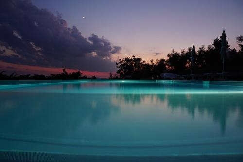 una piscina de agua con una puesta de sol en el fondo en Resort Orizzonti Glamping, en SantʼElpidio a Mare