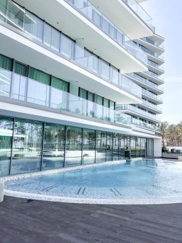 a large building with a swimming pool in front of it at Apartament Morski Widok Międzyzdroje in Międzyzdroje