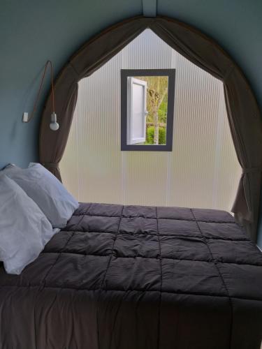 une chambre avec un grand lit avec une fenêtre dans l'établissement Camping Val de Boutonne, à Saint-Jean-dʼAngély