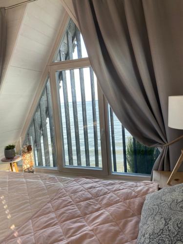 ein Schlafzimmer mit einem Bett und einem großen Fenster in der Unterkunft Vila Preiloja - Žvejo namelis in Neringa