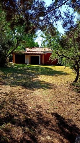 um edifício vermelho e branco num campo com árvores em Casa en Playas de Oro em San Antonio de Arredondo