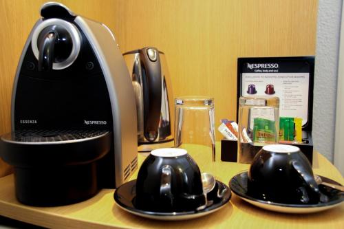 a coffee maker and two cups on a table at Novotel Birmingham Centre in Birmingham