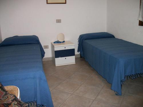 - 2 lits dans une chambre avec des draps bleus et une table dans l'établissement Terrazza sul mare, à Villaputzu