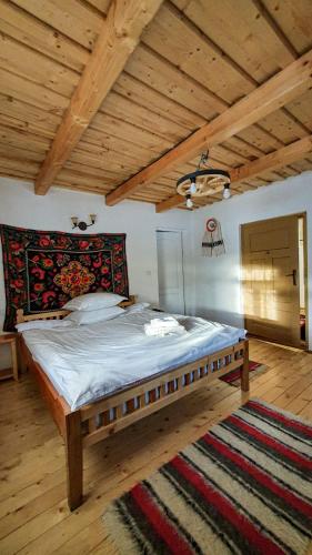 a large bed in a room with a wooden ceiling at Casuța din Grădină in Breb