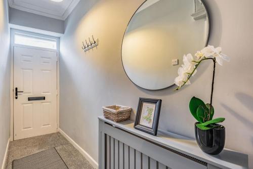 a hallway with a round mirror and a vase with flowers at 4 Segontium Terrace in Caernarfon