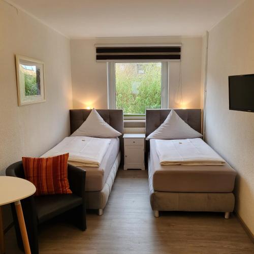 a room with two beds and a chair and a window at Hotel Pension Haus Irene in Hohwacht