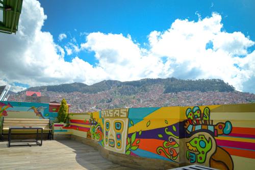 a colorful wall with a bench and a mountain at Hotel Las Brisas Centro in La Paz