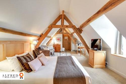 a bedroom with a large bed in a attic at Hôtel Saint-Laurent, The Originals Relais in Montfort-lʼAmaury