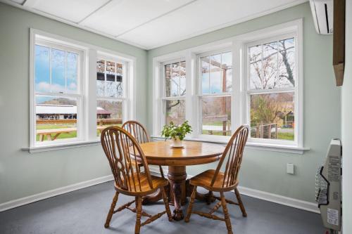 a dining room with a table and chairs and windows at Charming 4 bedroom farmhouse with large backyard for entertaining in Mountain City