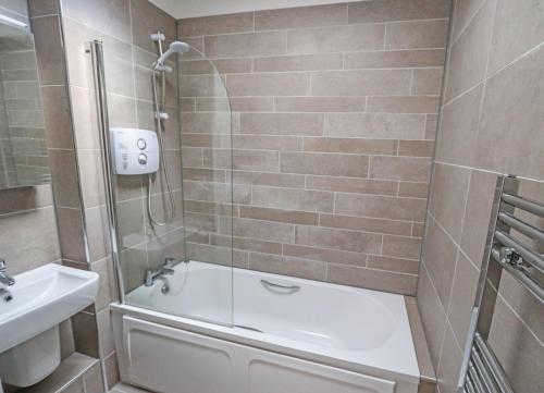 a bathroom with a shower and a tub and a sink at Churchmount Holiday Home Roundwood by Trident Holiday Homes in Wicklow