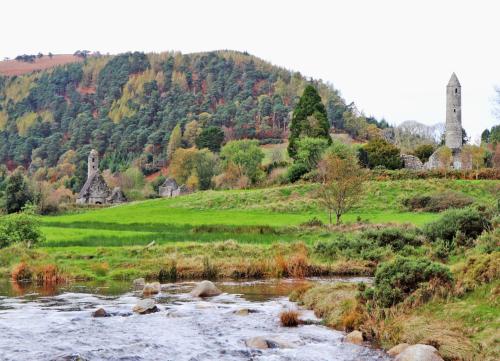 a river in the middle of a field with a mountain at Churchmount Holiday Home Roundwood by Trident Holiday Homes in Wicklow