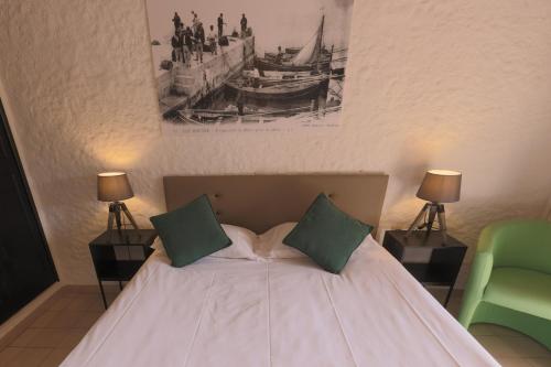 a bedroom with a white bed with two green pillows at Hôtel Casa Rossa & Spa in LʼÎle-Rousse
