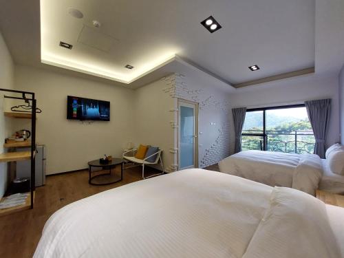 a bedroom with two beds and a tv on the wall at 清境依山舞林民宿 in Renai