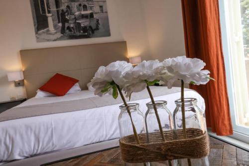 two glass jars with flowers in a room with a bed at Hôtel Casa Rossa & Spa in LʼÎle-Rousse