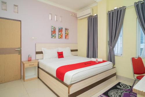 une chambre d'hôtel avec un lit et une chaise dans l'établissement RedDoorz Syariah Near Lapangan Dwiwarna Barabai, à Barabai