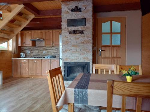 a kitchen and dining room with a table and a fireplace at Domki Letniskowe Komfort in Polańczyk