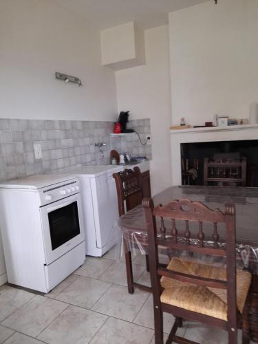 La cuisine est équipée d'une table et de plaques de cuisson blanches. dans l'établissement Maison dans écrin de verdure en Périgord noir, à Saint-Cyprien
