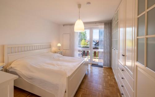 een slaapkamer met een wit bed en een groot raam bij Ferienwohnung Seeblick mit Blick auf die Alpen in Wasserburg