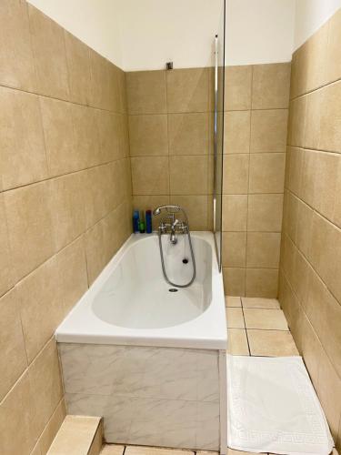 La salle de bains est pourvue d'une baignoire et d'une douche. dans l'établissement Spacious Entire Two Bedrooms Flat, H 3, à Great Yarmouth