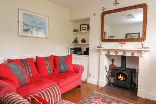a red couch in a living room with a fireplace at Coastguard Cottage in Dartmouth
