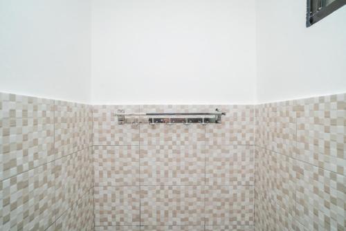 La salle de bains est dotée de murs carrelés marron et blanc. dans l'établissement Koolkost Syariah near Universitas Lambung Mangkurat Banjarmasin, à Alalak