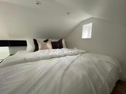 Cama blanca en habitación blanca con ventana en Adorable Tiny Home Garage Conversion Matlock Bath en Matlock