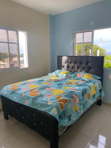 a bedroom with a bed with a colorful quilt at RESIDENCIAL DOÑA GLORIA in San Felipe de Puerto Plata