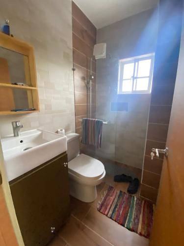 a bathroom with a toilet and a sink and a window at RESIDENCIAL DOÑA GLORIA in San Felipe de Puerto Plata
