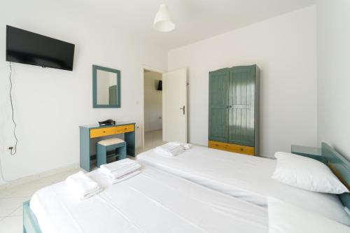 2 łóżka w pokoju z telewizorem i biurkiem w obiekcie SPIROS HOME w Lixoúrion