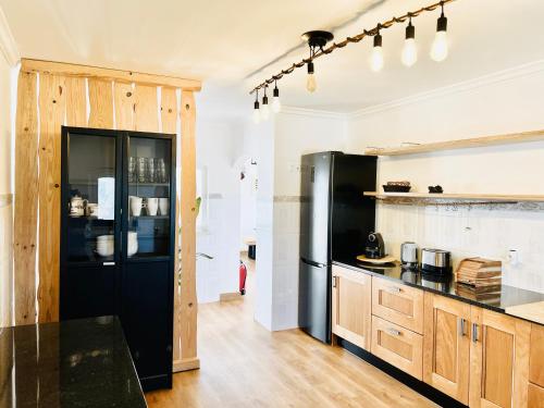 a kitchen with a black refrigerator and wooden cabinets at Ocean Tree Ferrel in Peniche