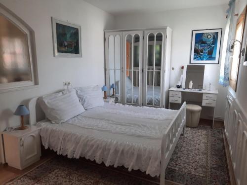 a white bedroom with a bed and a desk at Antal Apartmans Lunca de Sus Kulcsosház Gyimesfelsőlok in Lunca de Sus